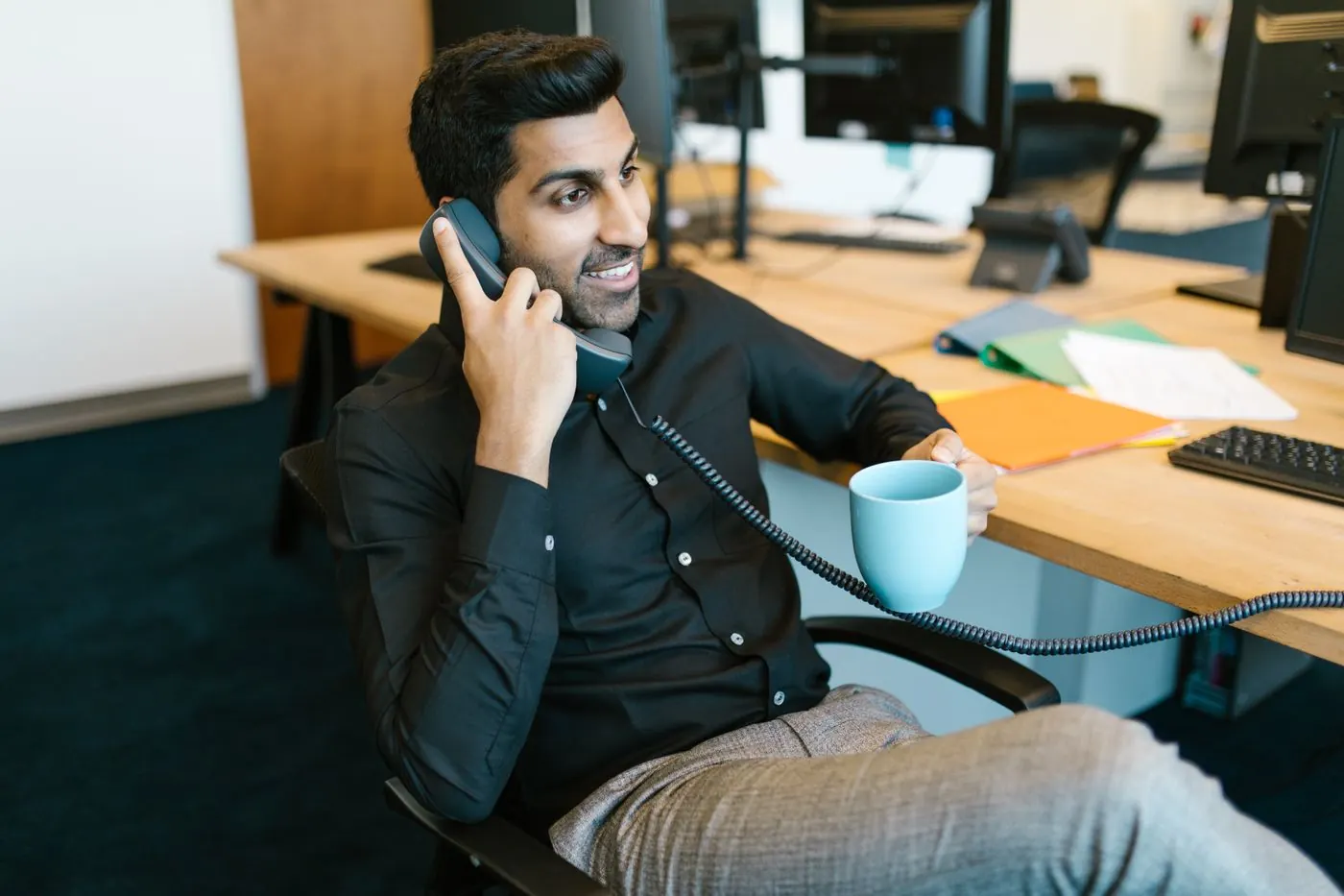 A man on a call at his desk, smiling