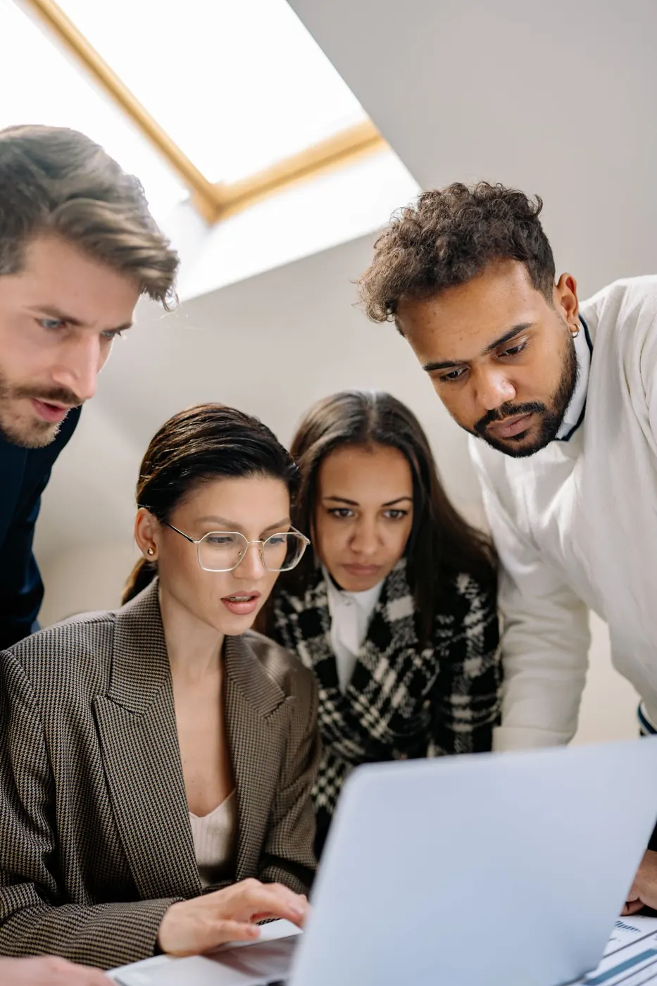Three colleagues looking at one laptop together
