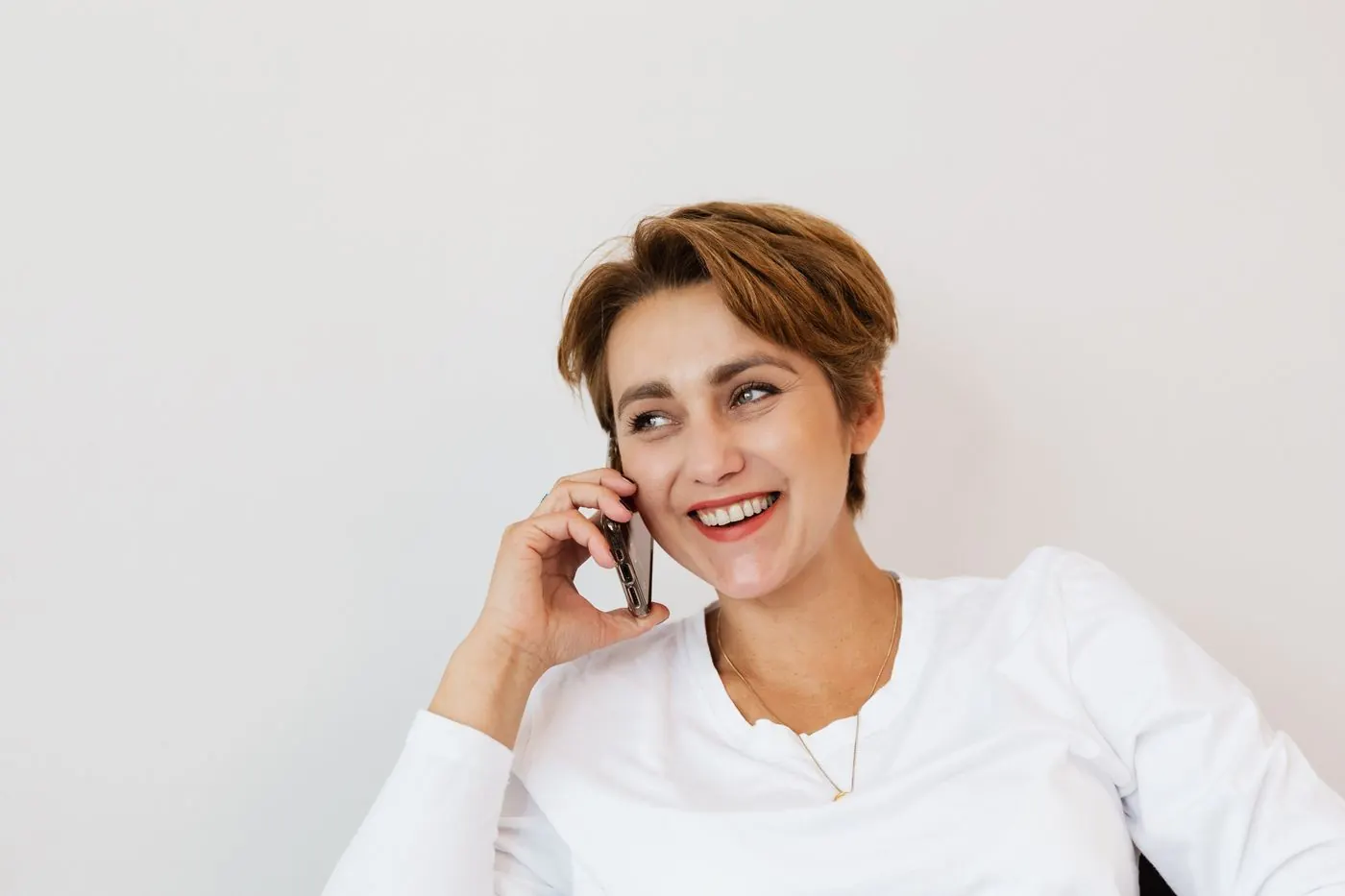A woman laughing on a phone call, relaxed